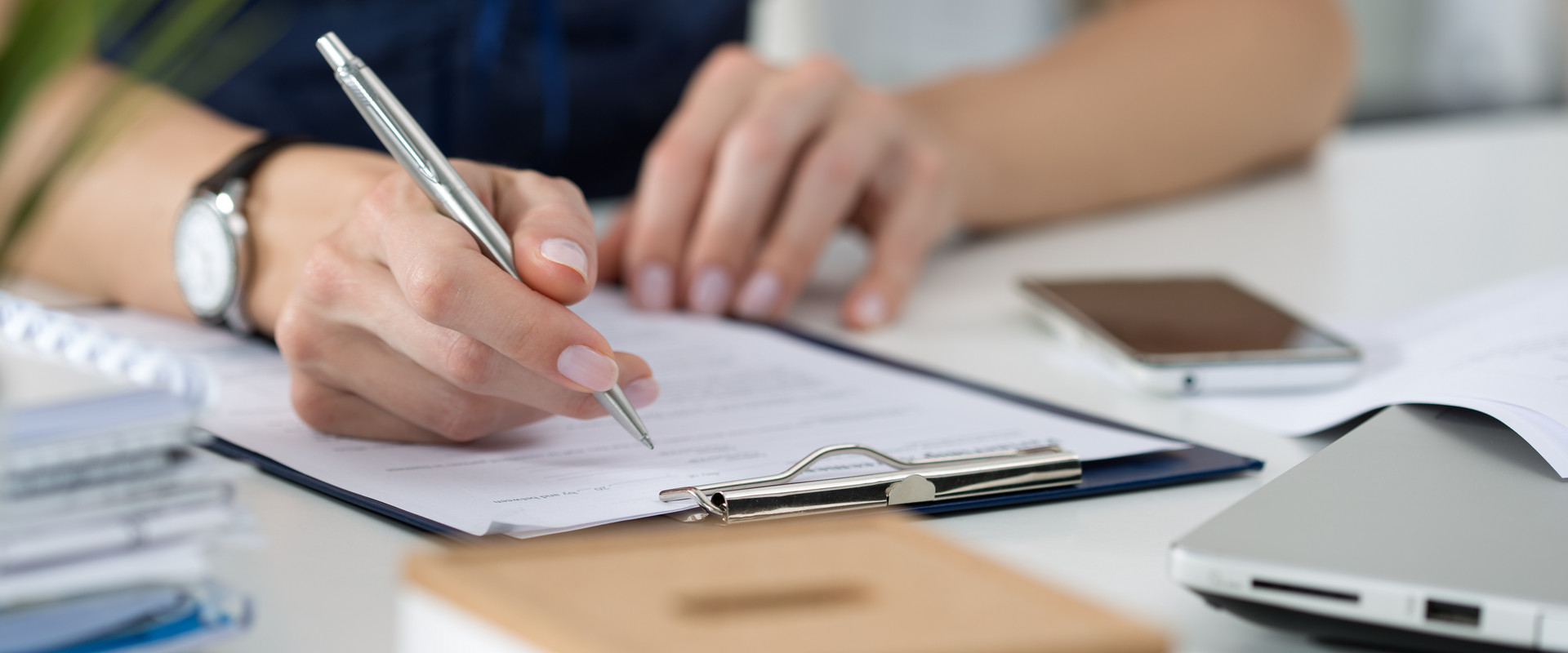 Nahaufnahme Hand mit Stift und Klemmbrett